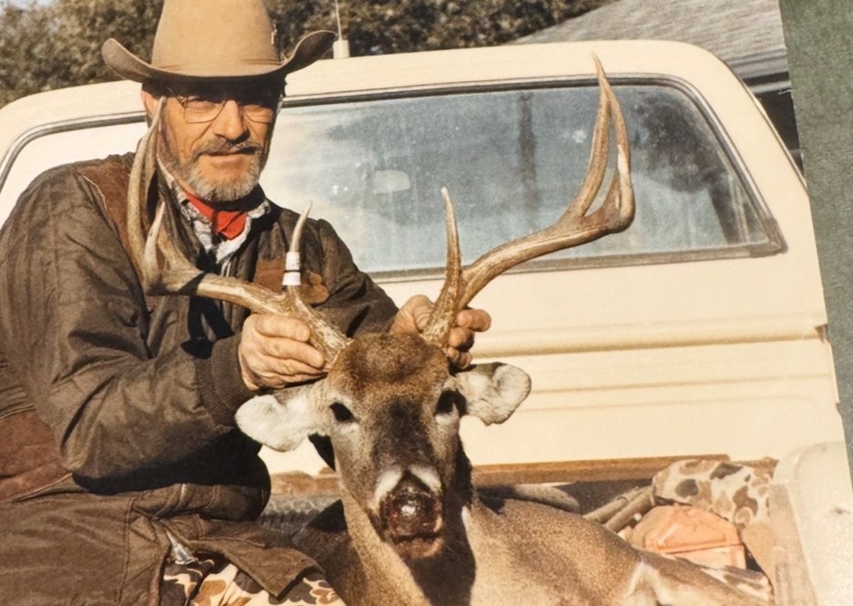 A man posing with a deer he hunted.