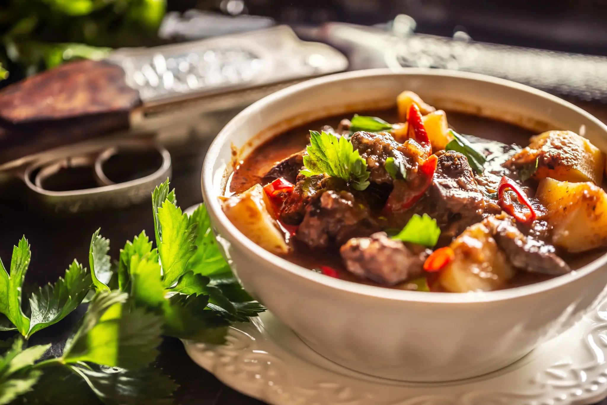 Hearty beef stew garnished with fresh herbs in a white bowl.